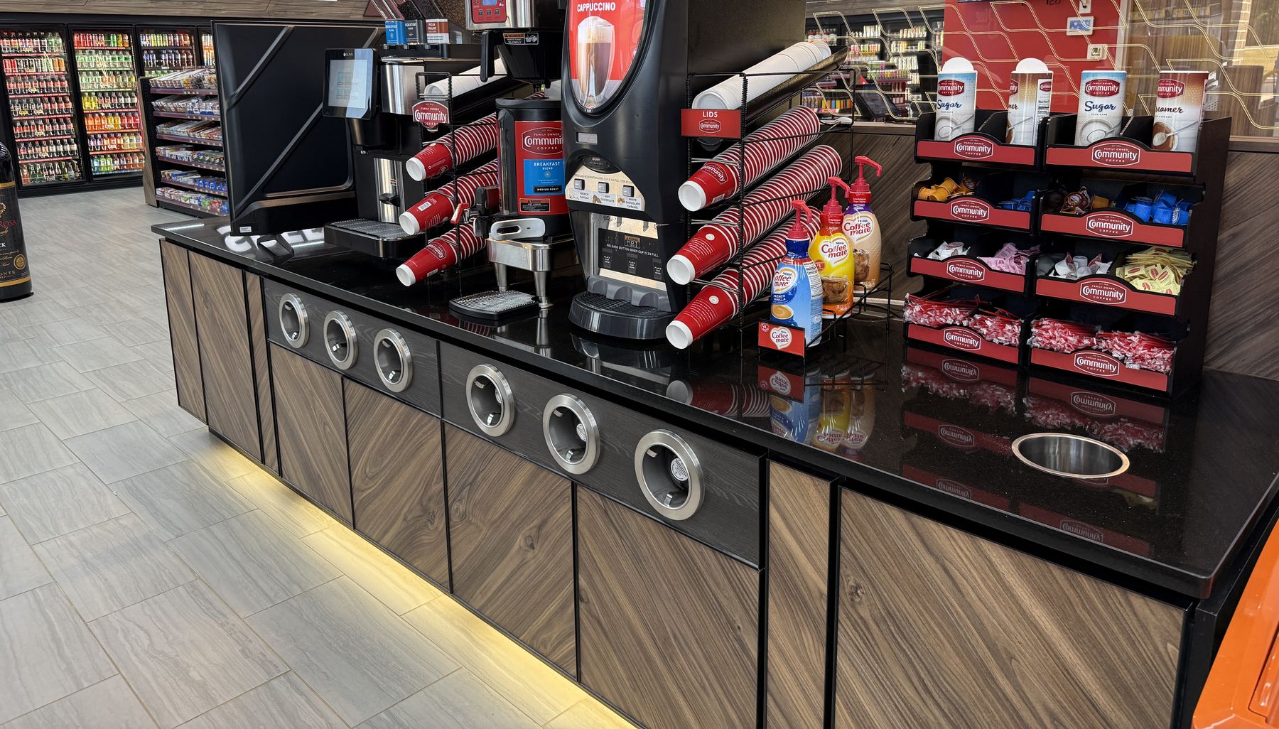 The coffee counter with brewers, stacked red Community Coffee cups and creamers